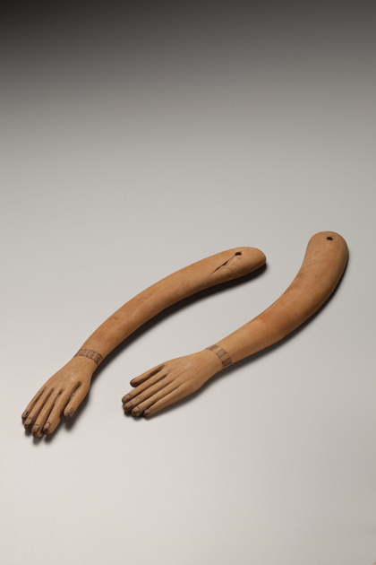 Image of two Ancient Egyptian wooden arms with hands laying flat on a grey surface